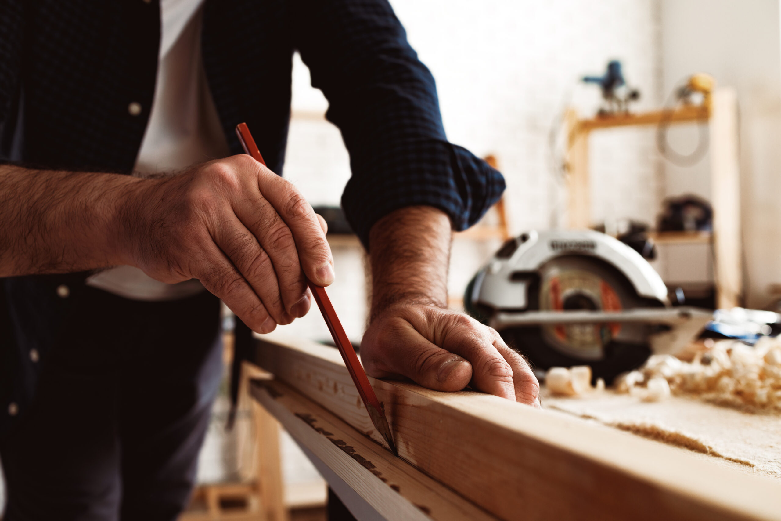 Carpenter makes pencil marks on a wood plank close up